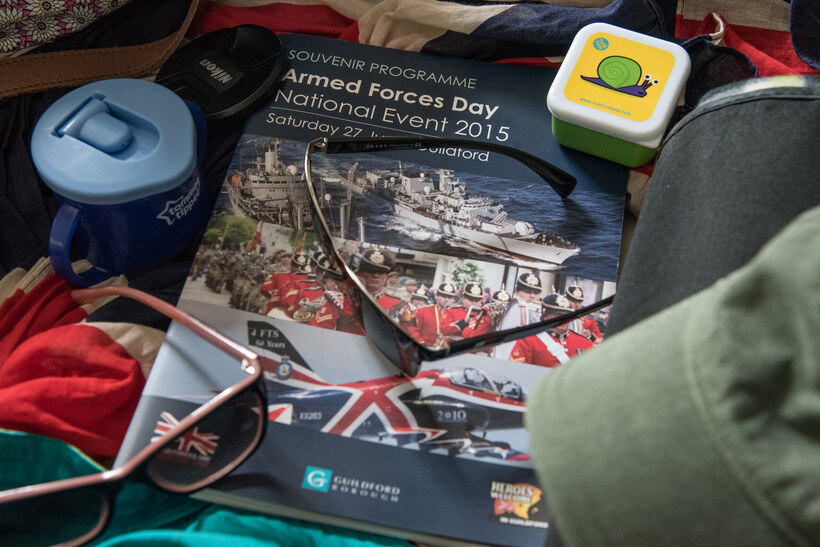 The brochure for Armed Forces Day in Guidlford surrounded by sunglasses and assorted items for a day out.