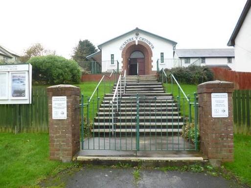 White painted brick building with steps leading to its front entrance. 