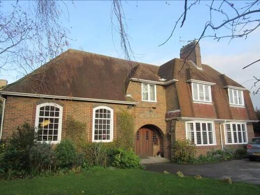 Large brick house with wide white windows and archway over double entrance doors. 