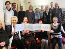 Group of people from Sheffield meeting around a poster saying 'let refugees learn'