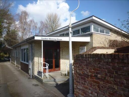 Off-white brick building with flat roofing and small ribbon of windows above the entryway. 