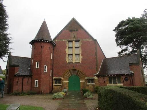 Imposing large brick building with three-storey tower and large decorative arches circling the entrance. 