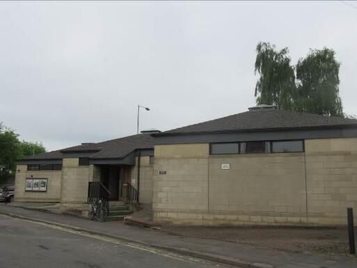 Single storey concrete building comprised of three connected blocks with pyramid-style roofs on each. 