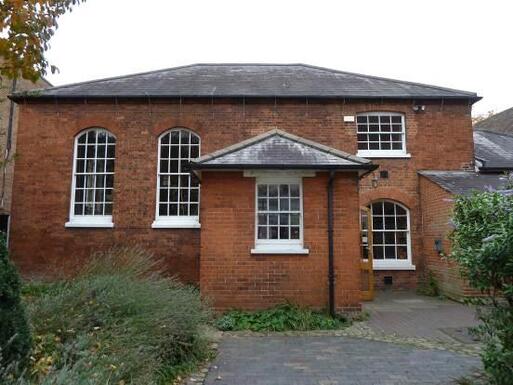 Redbrick split-level building with large entry porch and long windows on its left side.