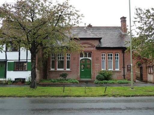 One storey brick building with decorative brickwork and green front door.