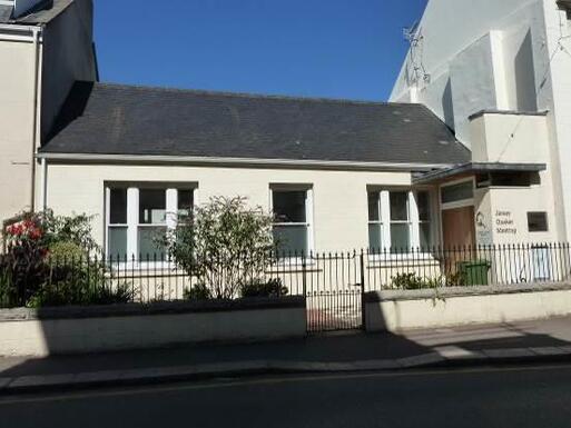 Low white painted building with Jersey Quaker Meeting lettering painted on the right entrance porch.