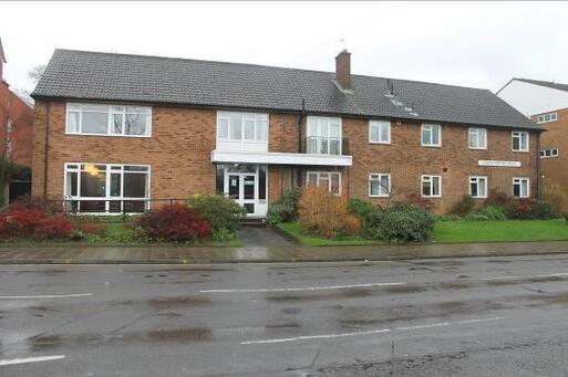 Two-storey house with wide white windows and accessible slope to front.