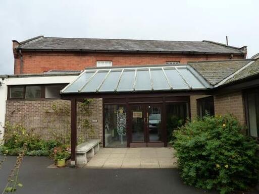 Plain brick building with brown plastic frame door under a roof.