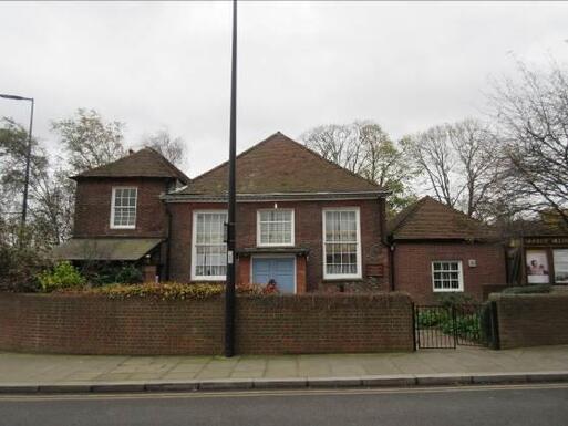 Covered by low brick wall house with big windows and blue doors.