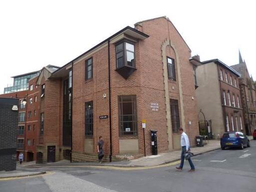 Relatively modern building with inscribed panel adjacent to entrance.