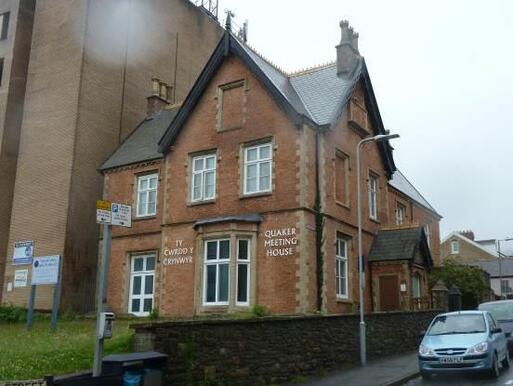 Brick laid building with sign 'Quakers Meeting House' and  original entrance with the datestone.