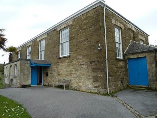 Single-storey house with two porches built from local stone with blue doors.