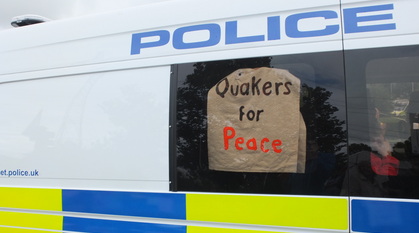 A Quakers for Peace sign in the window of a police van, held up by Quakers arrested inside