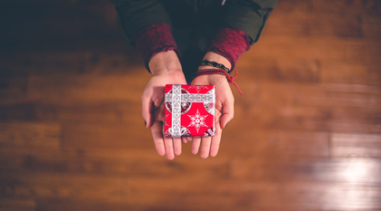 two hands outstretched holding a Christmas gift