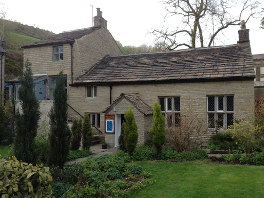 Two storey stone building set in large gardens with long windows and porch