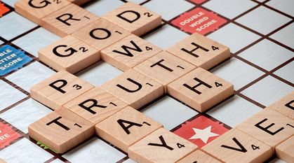 A scrabble board with the words God, growth, truth, prayer, believer spelt out.