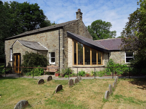 Small stone cottage with wide front porch with lawned grounds.