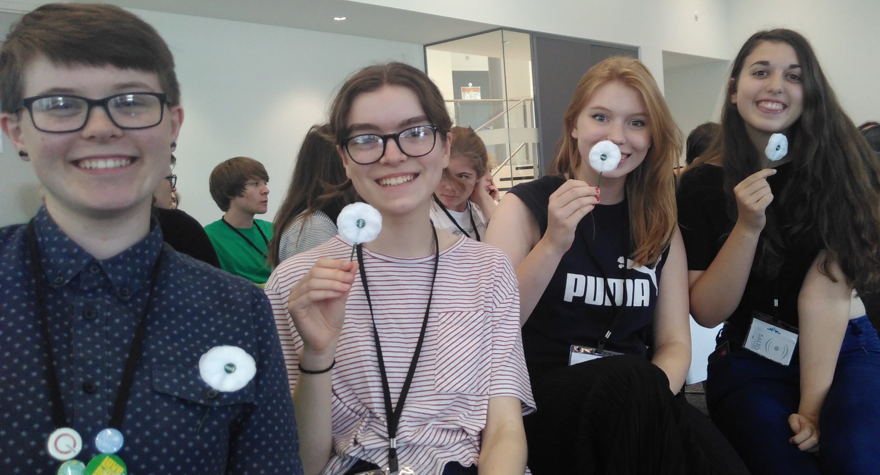 4 young people hold white poppies