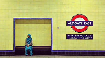 Woman sitting in Aldgate Tube station.