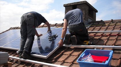 two men installing solar panels on a roof