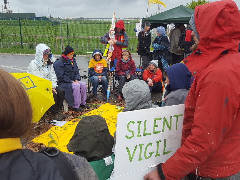 adults seated circle silent vigil rainy