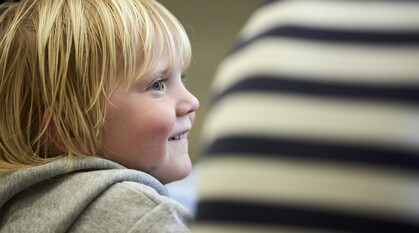 child sitting next to an adult in meeting for worship looking gleeful