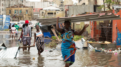 People clearing debris and carrying sheets of corrugated iron through floodwater