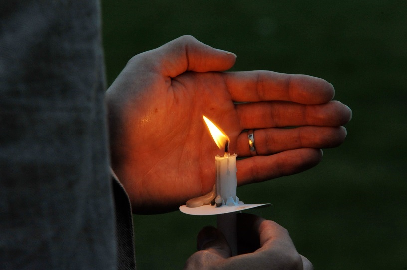 hand cradling candle in darkness