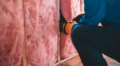 Person fitting a house walls with insulation