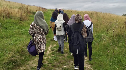 young people walking up a hill on a cloudy day