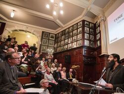 a person giving a speech to a room full of people