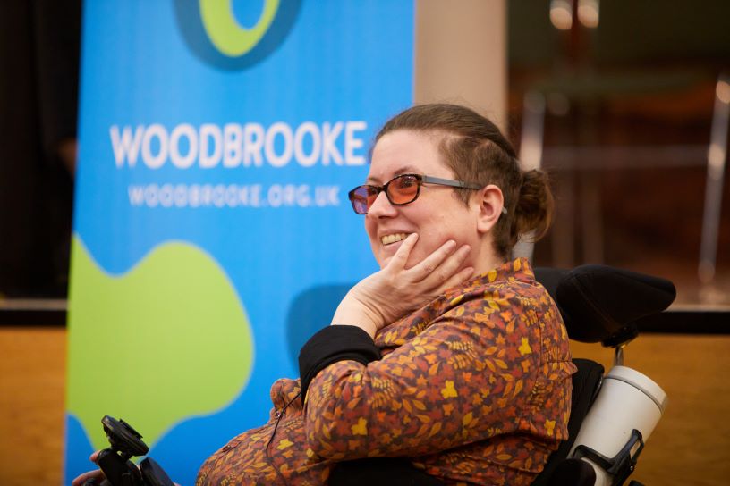 Woman in wheelchair in front of banner