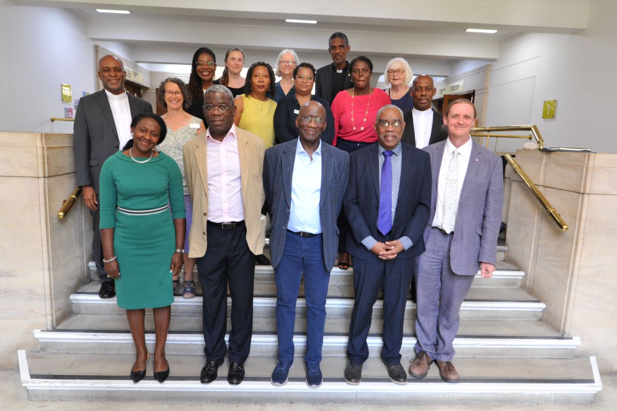 A delegation of Jamaican church leaders standing on some steps with Quakers and Quaker staff 