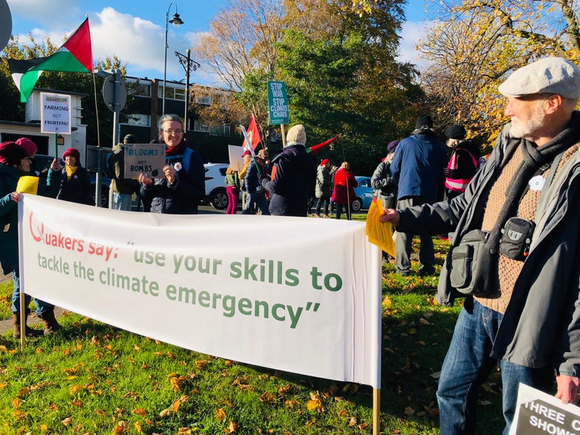 A group of Quakers amongst a wider protest holding a banner saying "use your skills to tackle the climate emergency"