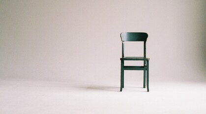 An empty green chair in a white room