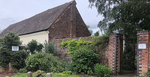 Brick building partly obscured by a gated wall