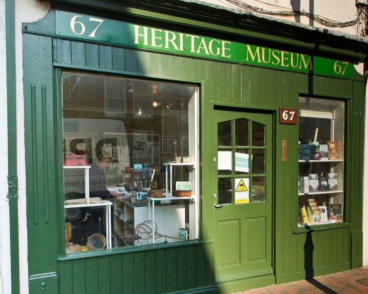 Green shoplike front of Sittingbourne Heritage museum, with big lass windows and door. 