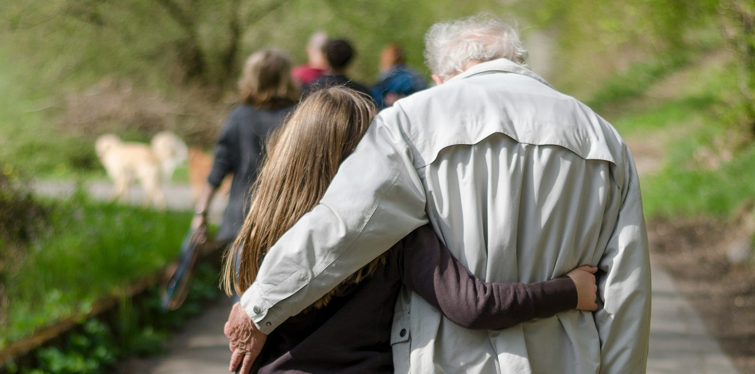 A picture of a grey-haired man and a child walking side by side.