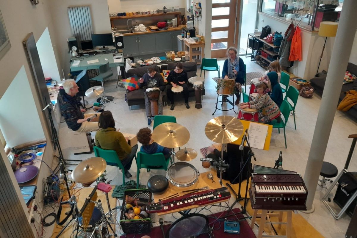 Music studio with drums, keyboards etc and people playing