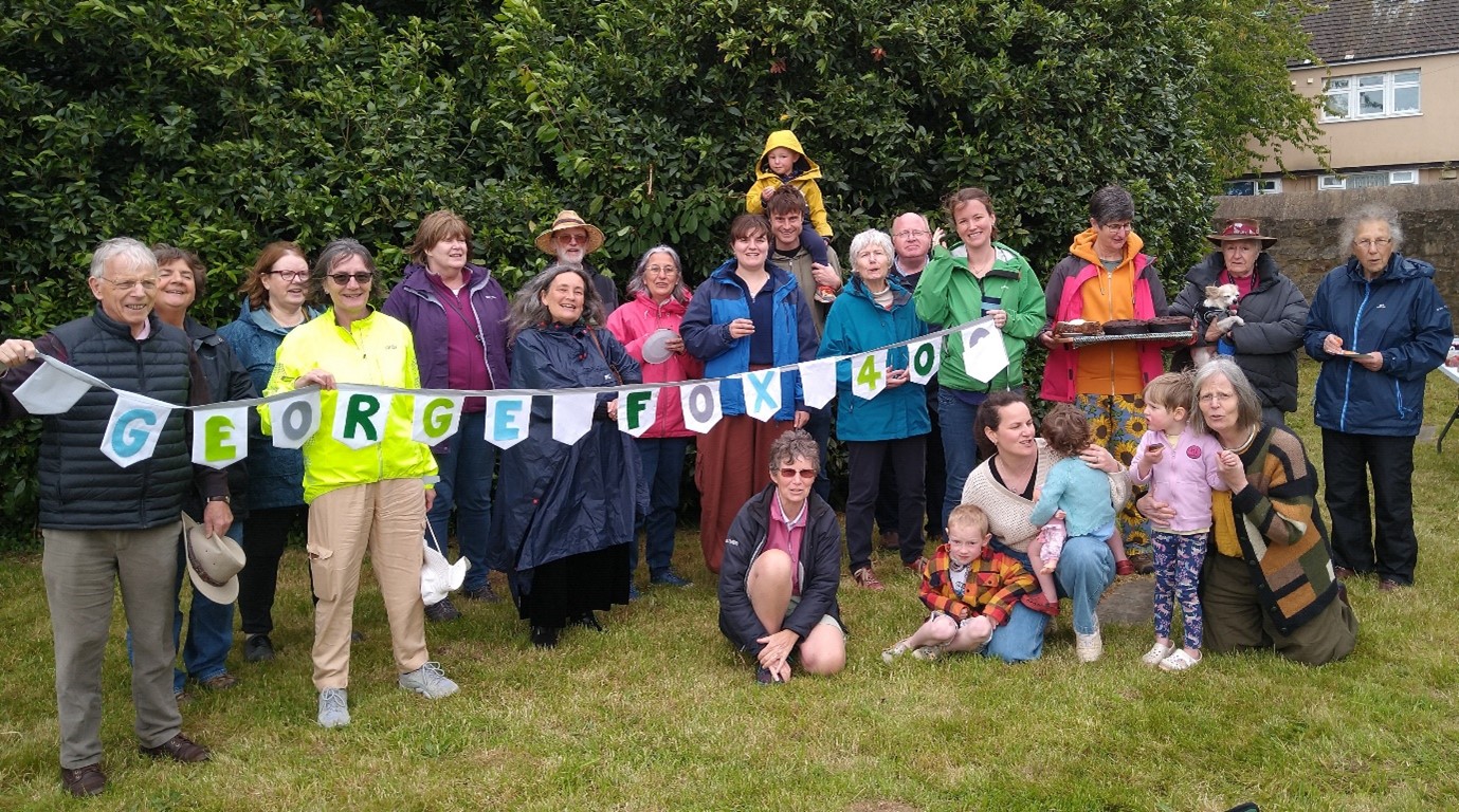 group of people standing/kneeling on grass, holding bunting reading george fox 400. 