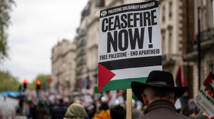 At a Palestine solidarity march in London a man in a hat marches head down carrying a placard that reads "CEASEFIRE NOW! Free Palestine. End apartheid"