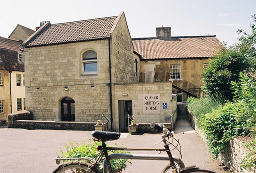 Stone townhouse with rounded windows and large 'Quaker Meeting House' sign.