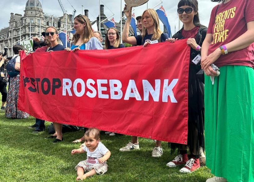 Baby sitting in front of Stop Rosebank banner