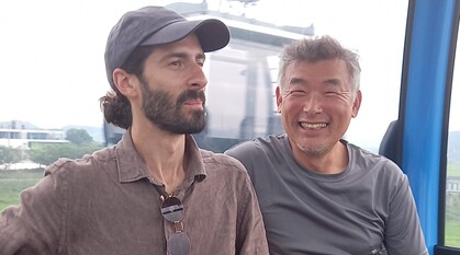 An image of two men - on the right of the image is Bongsoo Kwag - sitting in a cable car over the DMZ