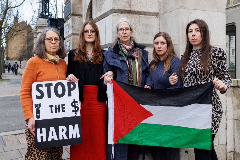 Five women standing with banners outside court