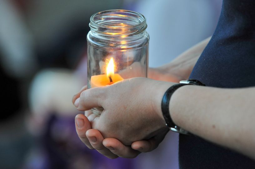 Lit candle cupped in hands
