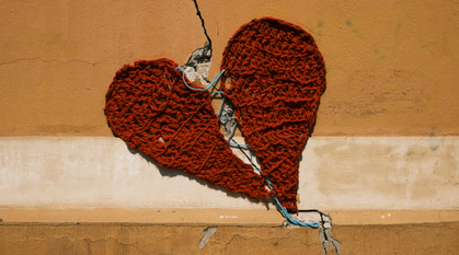 A textile art red heart hanging on a cracked wall, not hiding but working with texture of the wall.