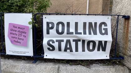 A sign saying 'polling station' outside a polling station, alongside another poster reminding people to bring Voter ID in order to vote