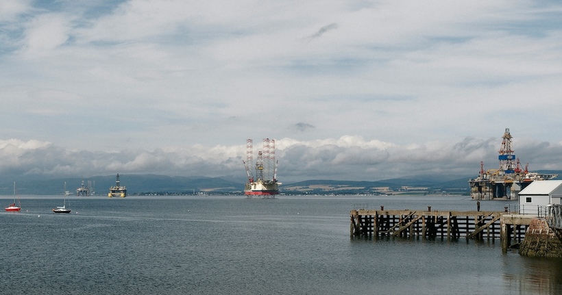 In the midst of a climate emergency we need to speed up our transition away from fossil fuels. Photo: Oil rigs in Cromarty Firth by <a href="https://unsplash.com/@blinky264?utm_source=unsplash&utm_medium=referral&utm_content=creditCopyText">Marc Pell</a> on <a href="https://unsplash.com/photos/sailboats-and-a-pier-on-a-calm-sea-P-W94svJNLc?utm_source=unsplash&utm_medium=referral&utm_content=creditCopyText">Unsplash</a>.
