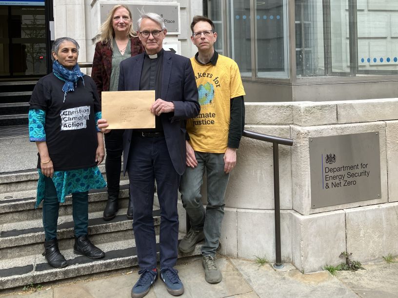 Four people holding a letter in front of a government department